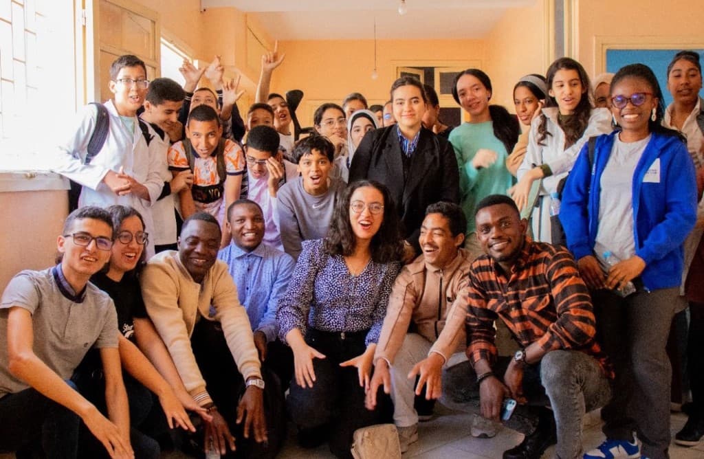 Diverse group of youth participants and facilitators smiling together after a community workshop
